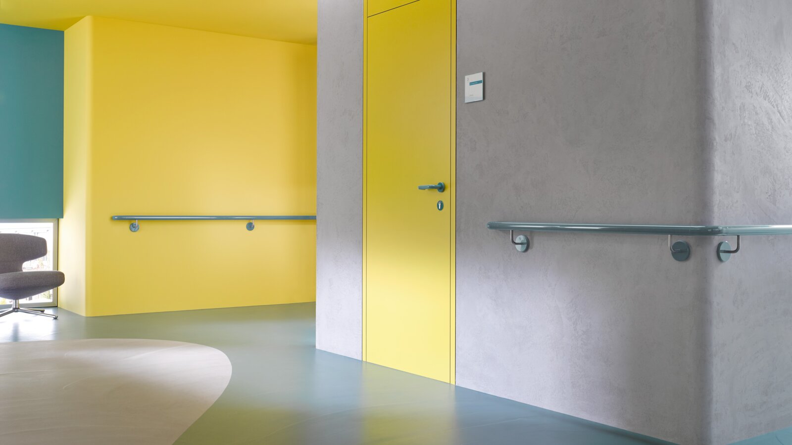 Corridor in a care building equipped with handrails in the color aqua blue