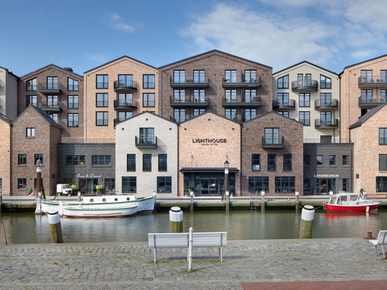 Havenbekken met boten; aan de overkant van de oever staan moderne bakstenen huizen