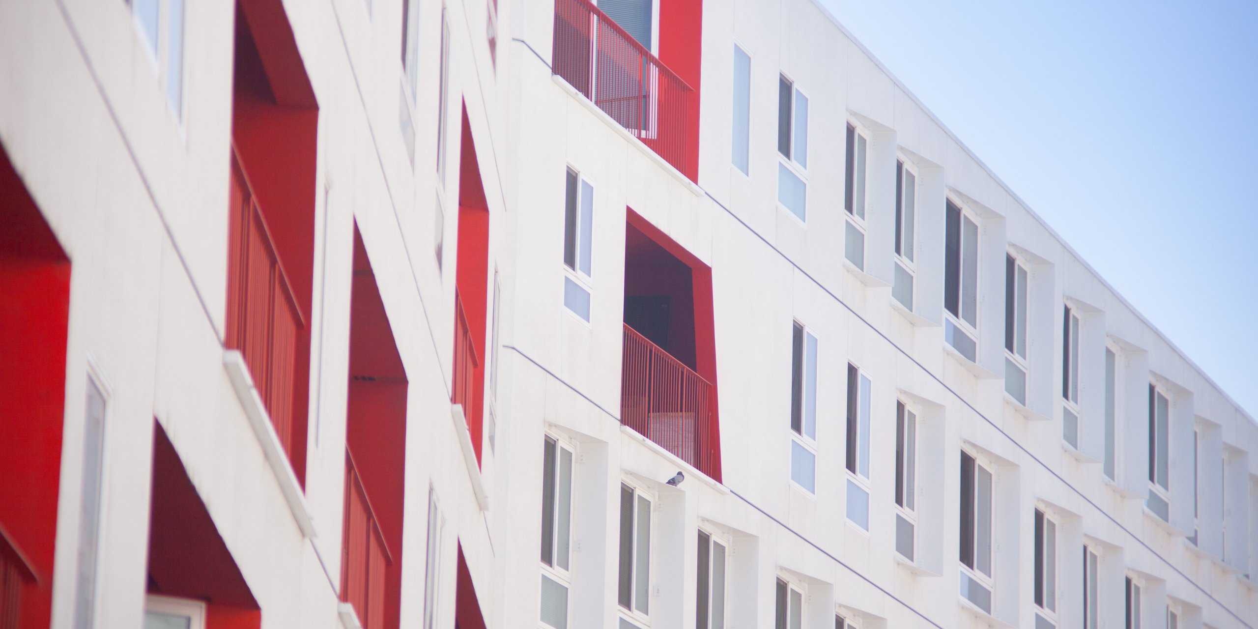 White exterior façade of a care home with occasional red-painted window walls